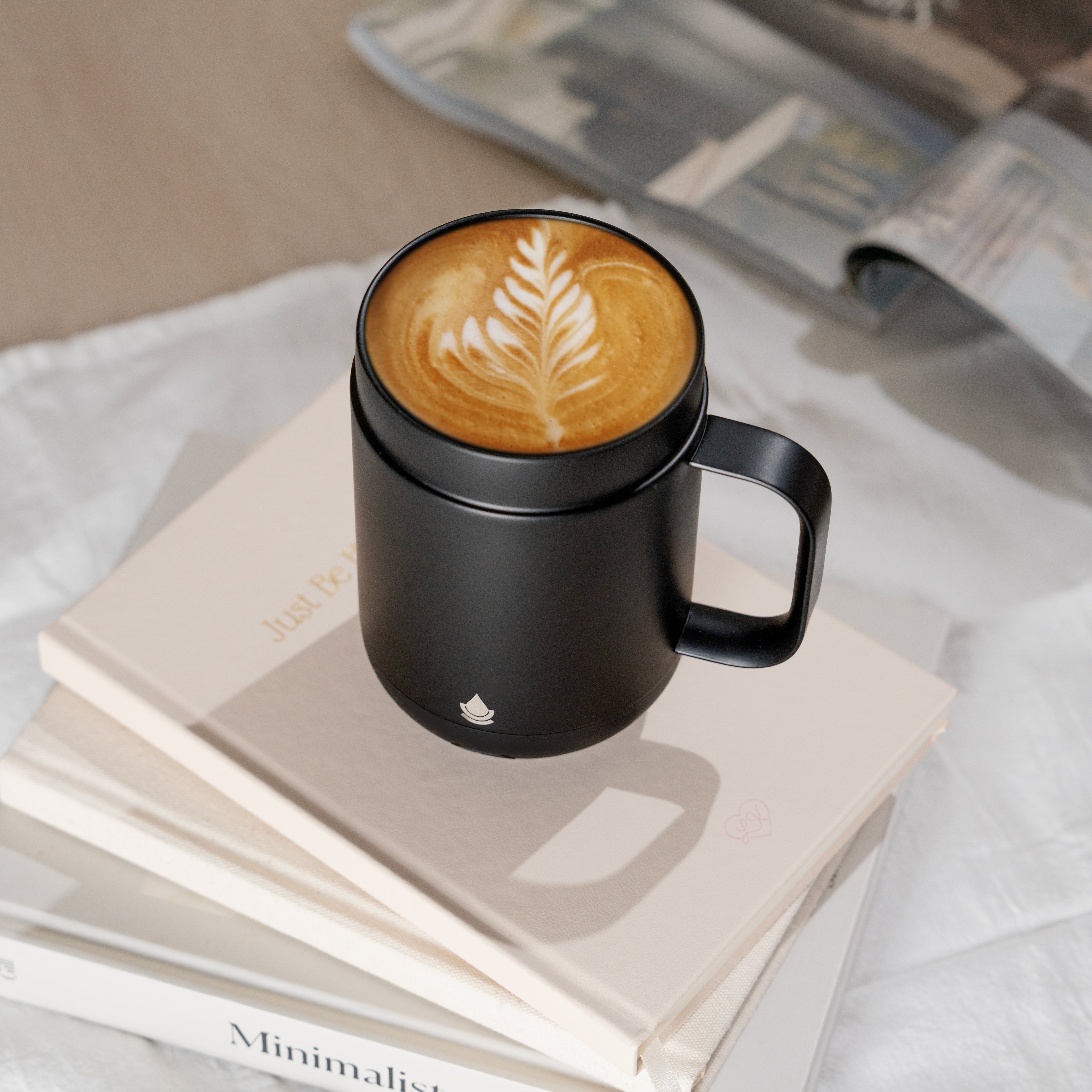 A Ciups Mug self heating coffee while sitting on a stack of books